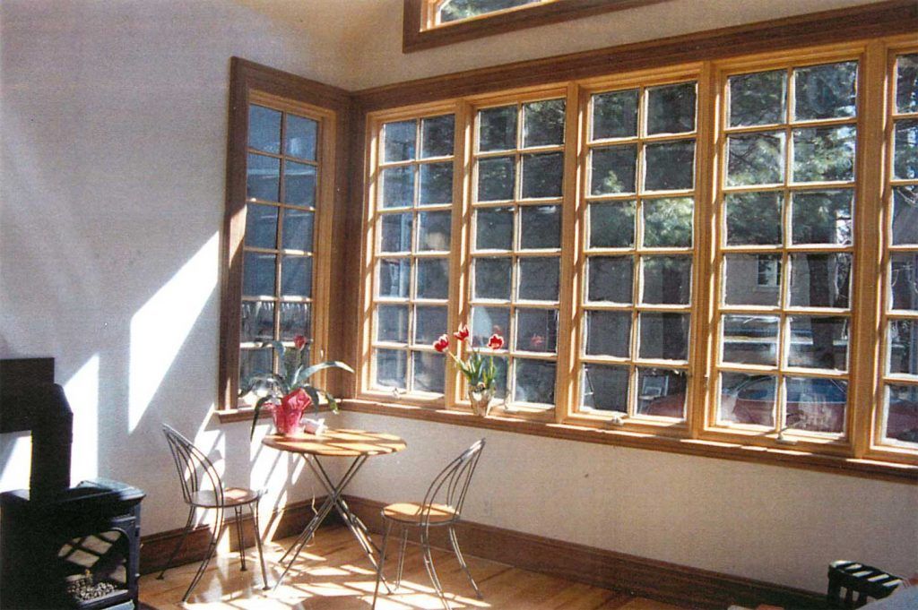 A living room with lots of windows and a table and chairs