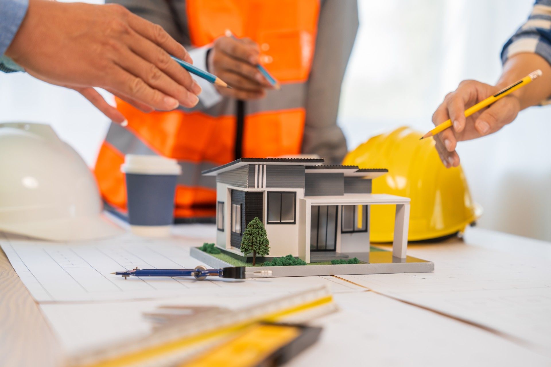 A group of people are working on a model house on a table.