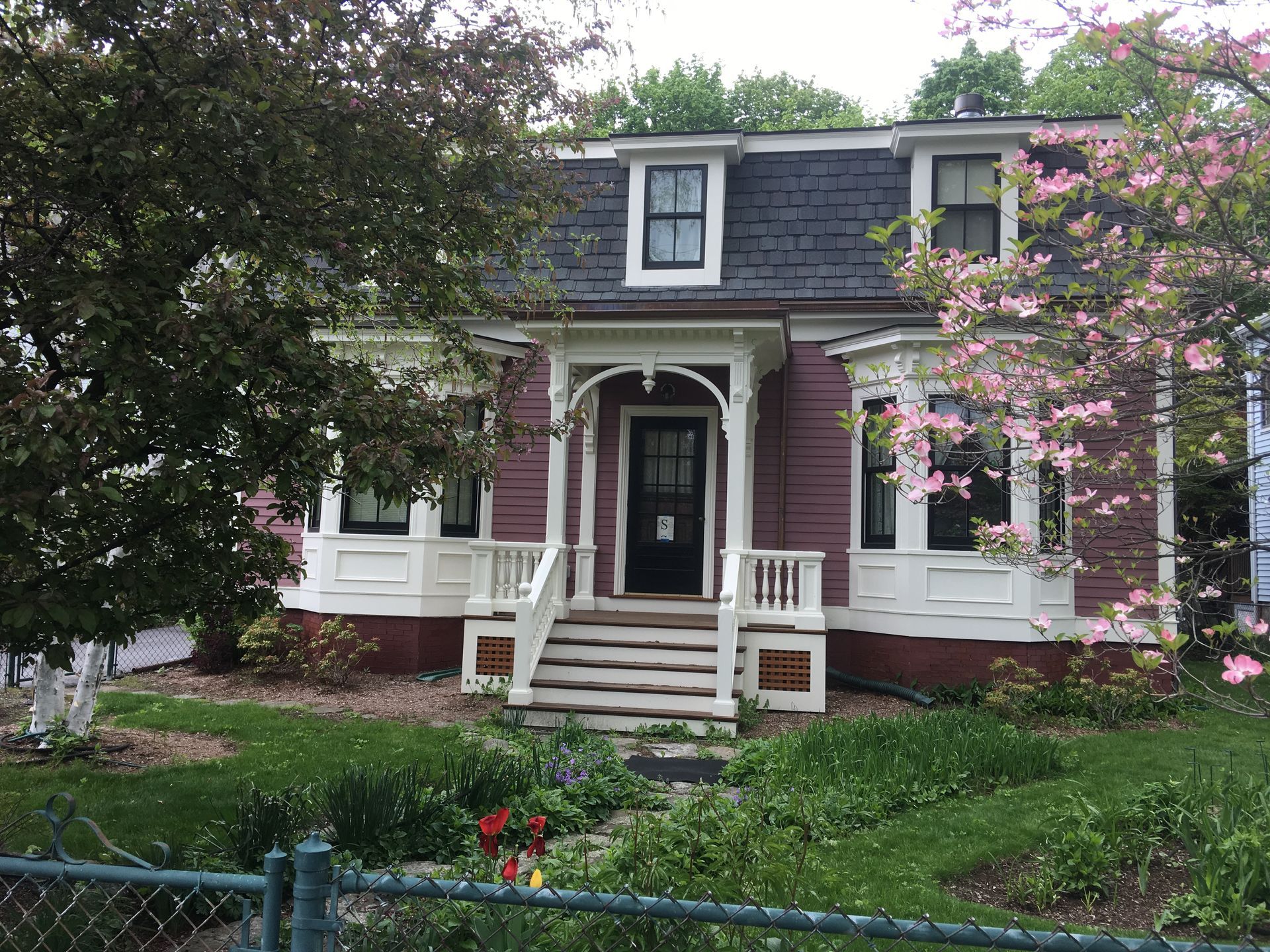 A purple and white house with a black roof and a porch