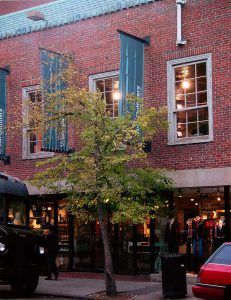 A red car is parked in front of a brick building