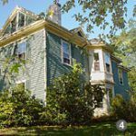A large house with a lot of windows is surrounded by trees and bushes.