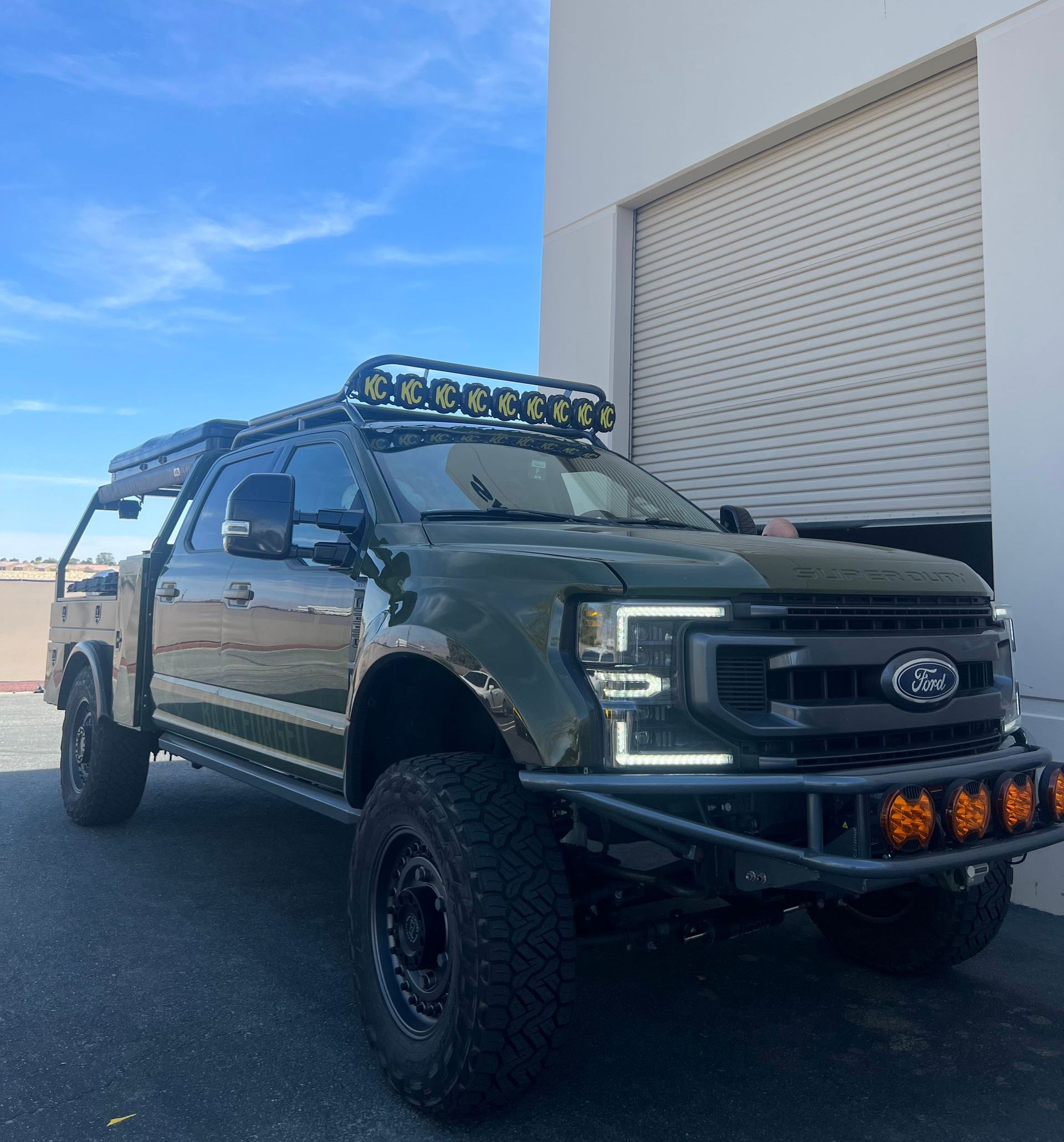 A green ford truck is parked in front of a garage door