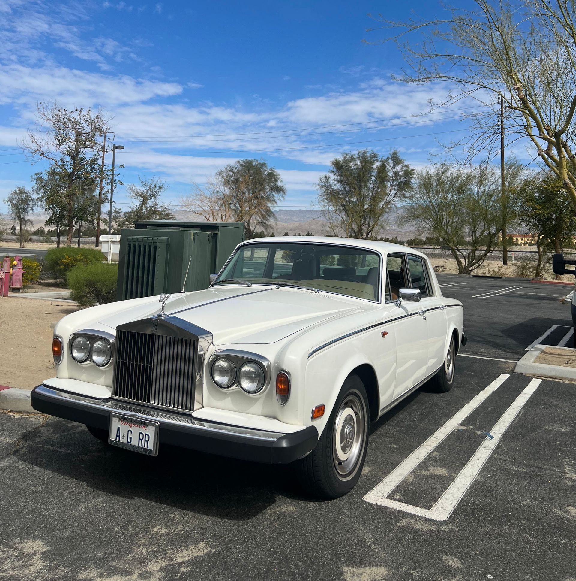 A white rolls royce is parked in a parking lot