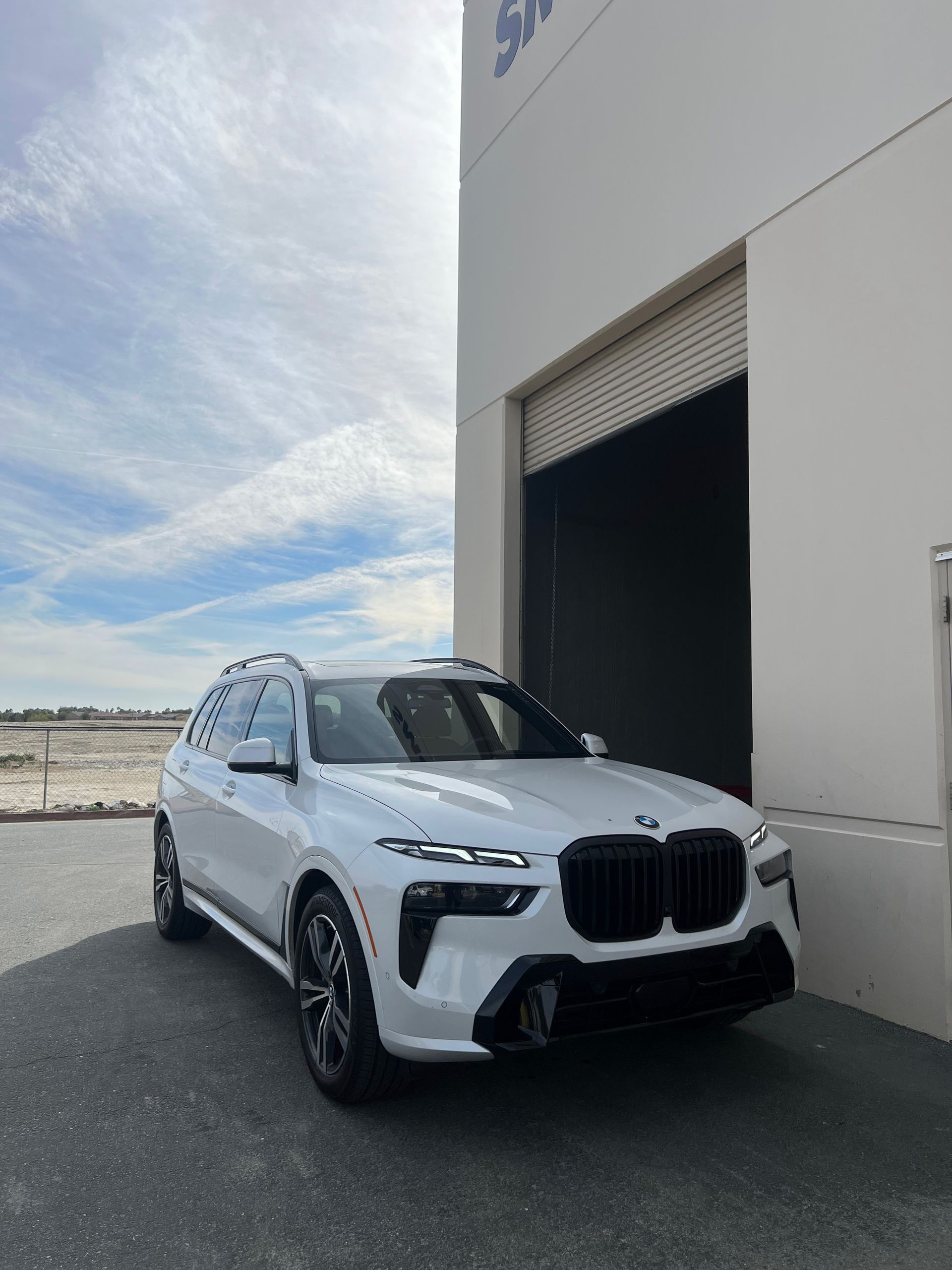 A white car is parked in front of a building.