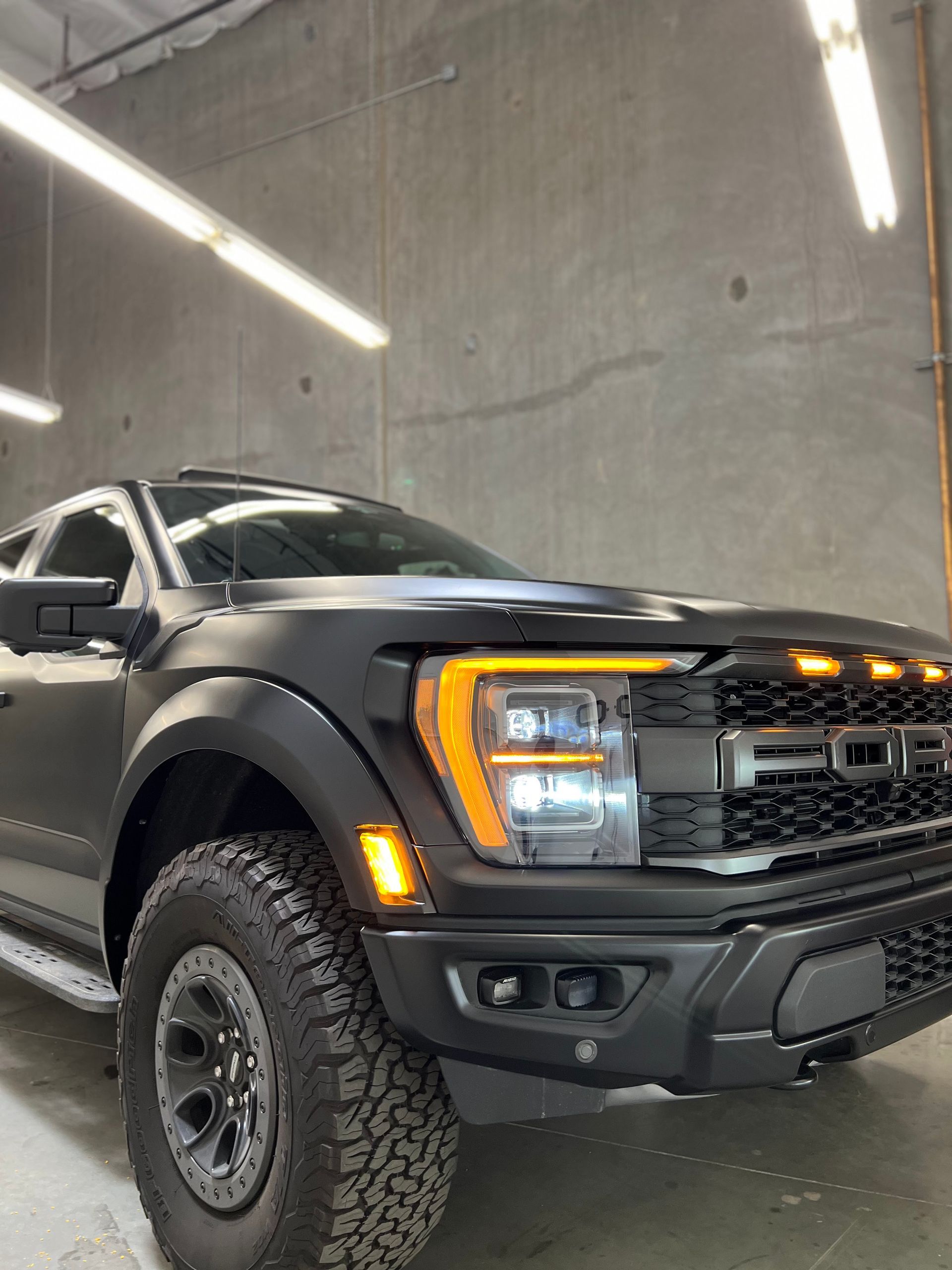 A black ford raptor is parked in a garage.