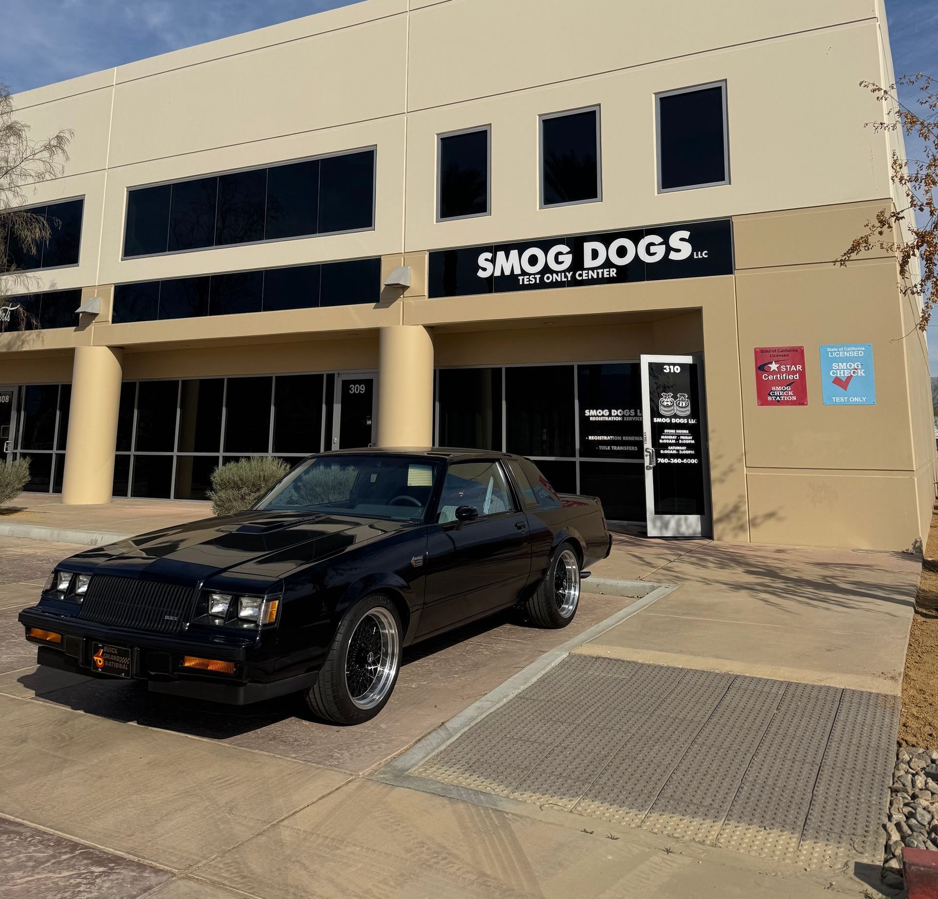A black car is parked in front of a smog dogs building