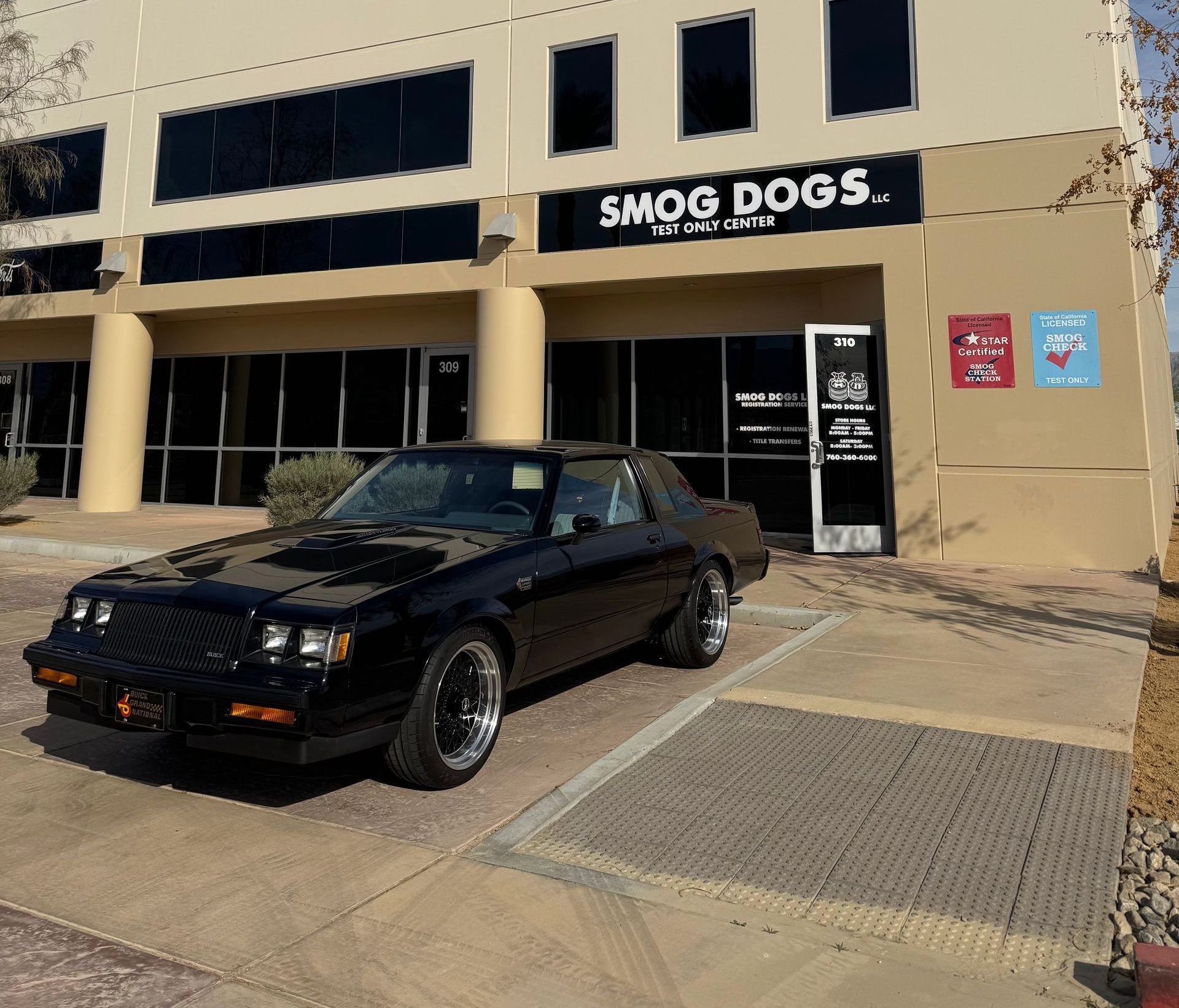 A black car is parked in front of a building that says smog dogs