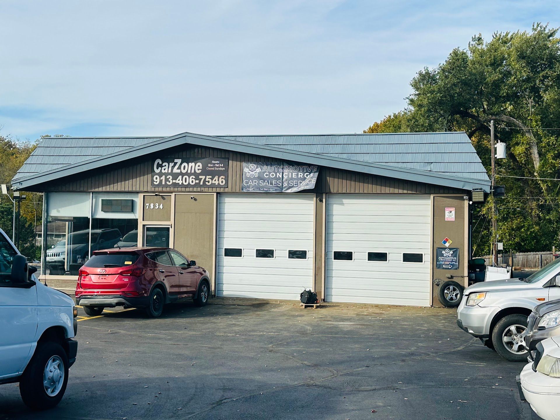 Car Zone auto repair shop with garage doors, red SUV, and parked cars | Automotive Concierge KC