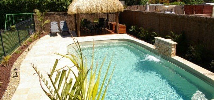 A swimming pool with a thatched hut in the background-Swimming Pool in Bundaberg, QLD