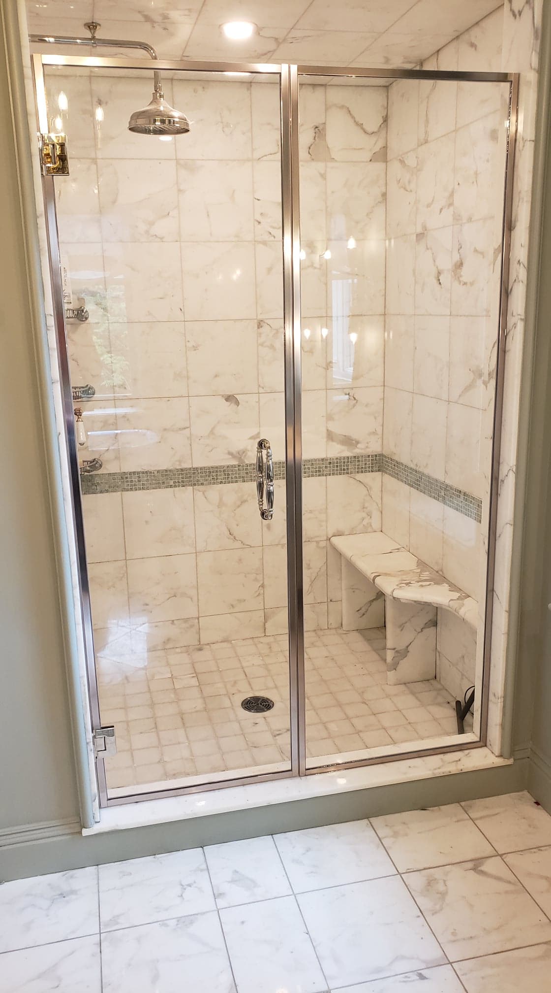 Une salle de bain avec une douche à l'italienne et un banc.