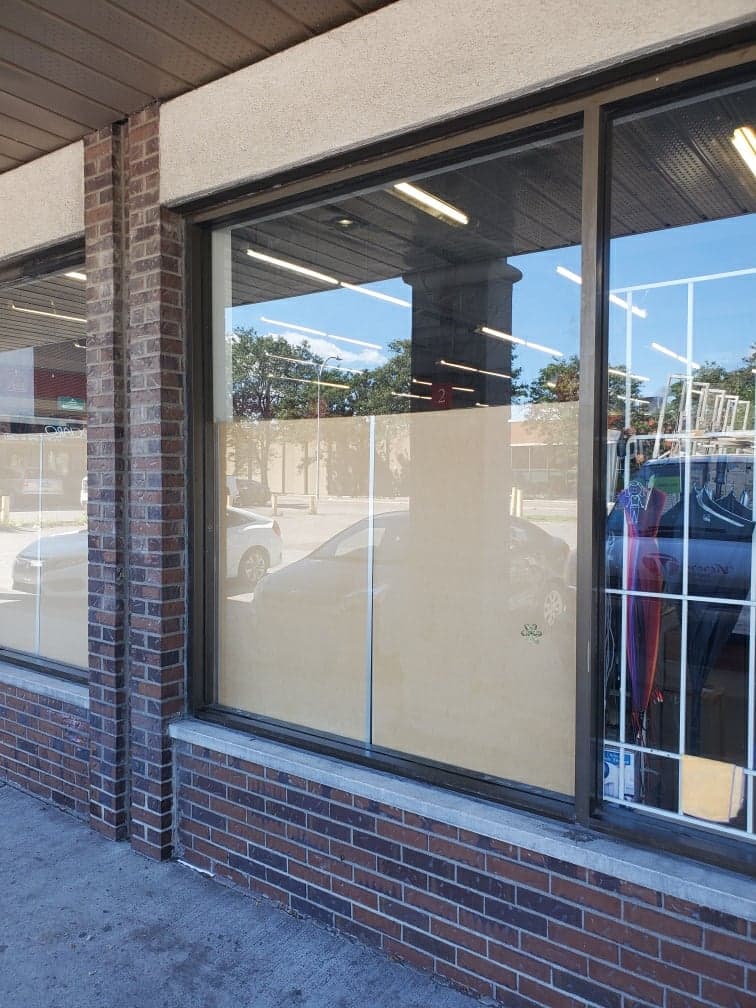 Un bâtiment en briques avec une grande fenêtre et le reflet d'une voiture dans la fenêtre.