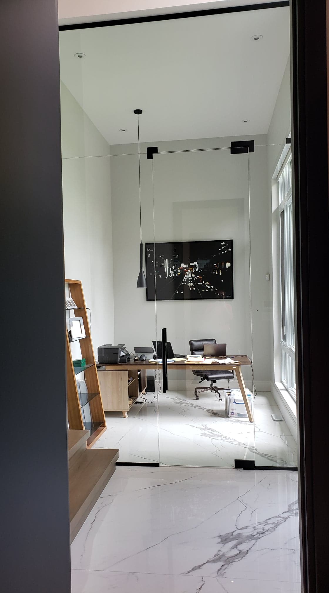 Une pièce avec un bureau, une chaise et une télévision au mur.