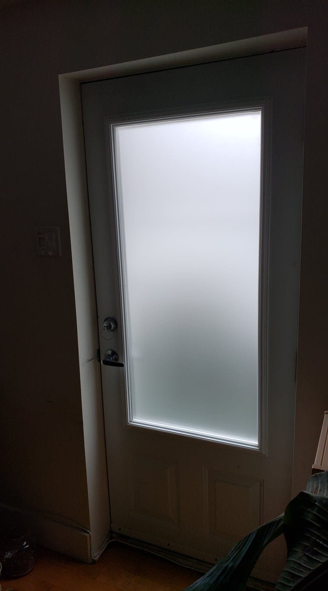 Une porte blanche avec une fenêtre en verre dépoli dans une pièce.