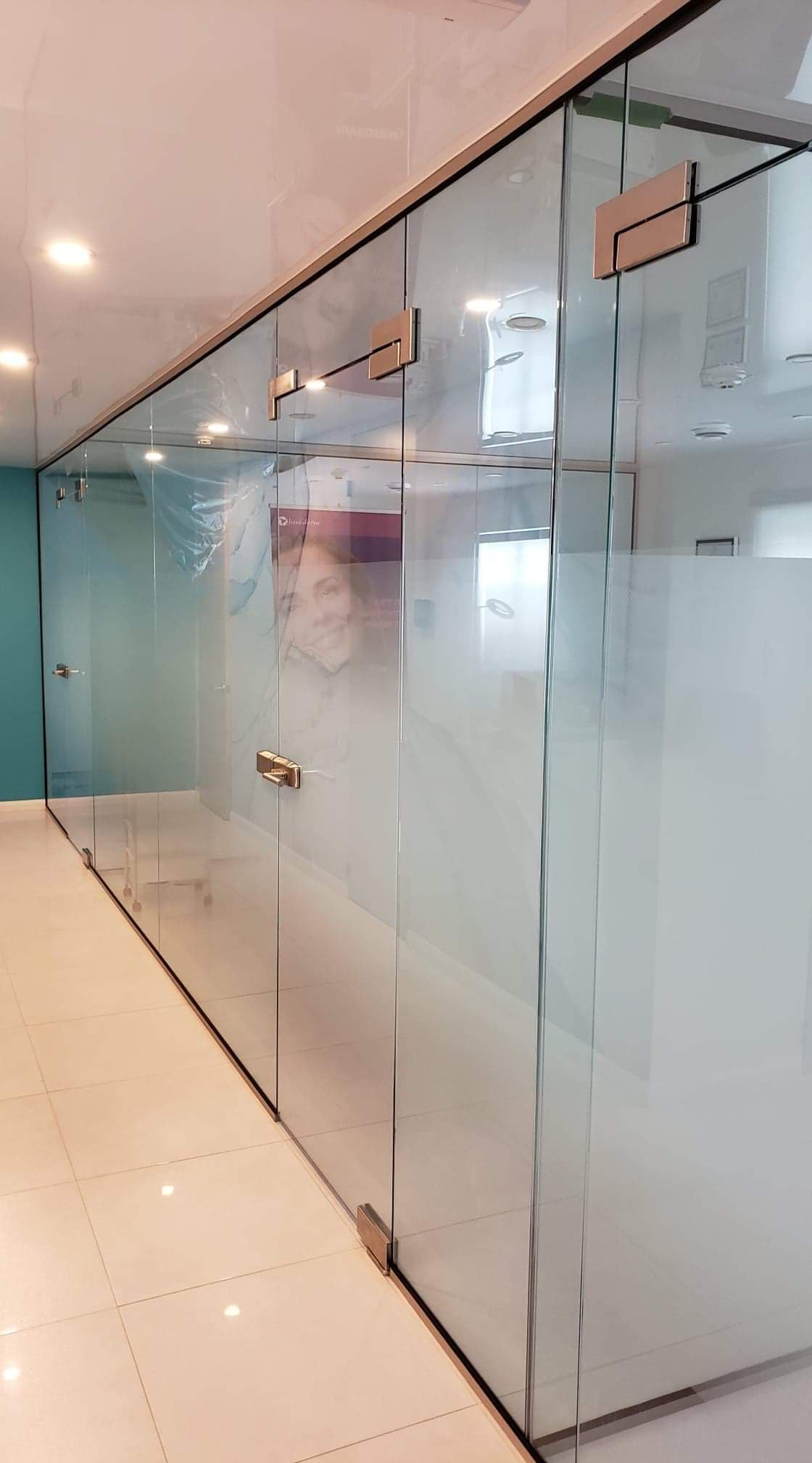 Un couloir avec beaucoup de murs et de portes en verre.