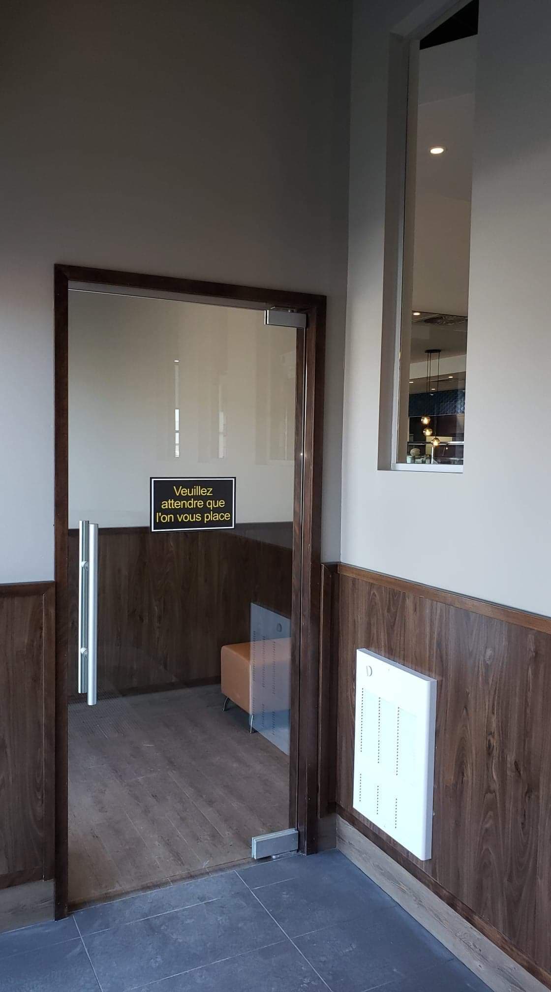 Une porte vitrée est ouverte sur une pièce avec des boiseries et une fenêtre.