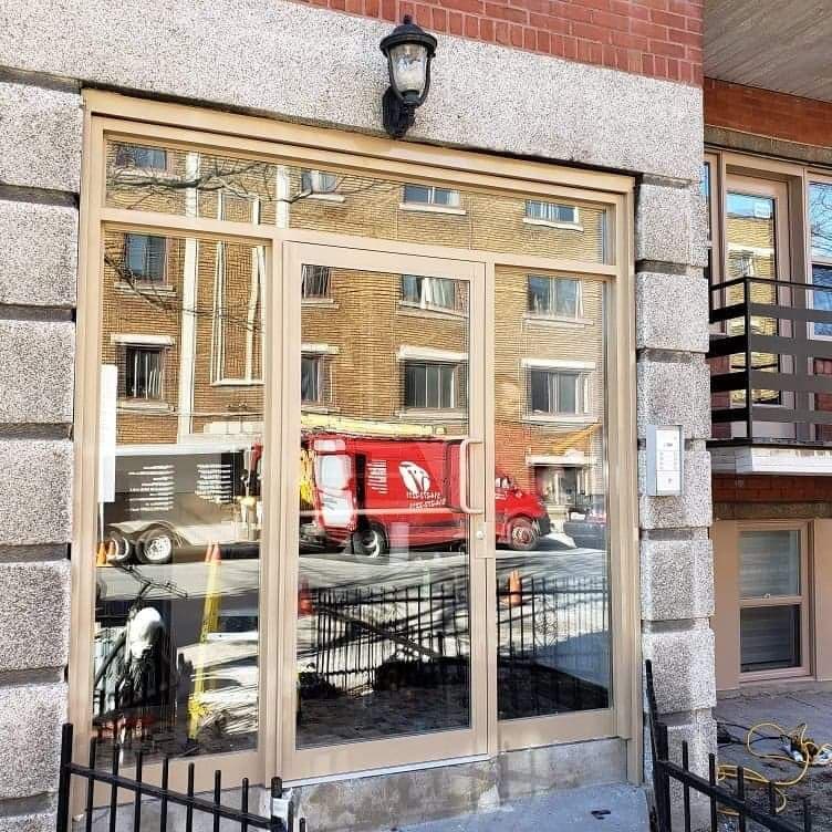 A red truck is reflected in the glass doors of a building