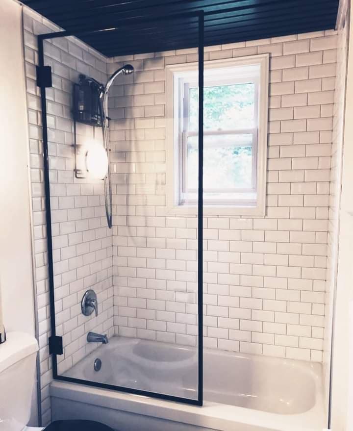 Une salle de bain avec des murs en briques blanches et une baignoire