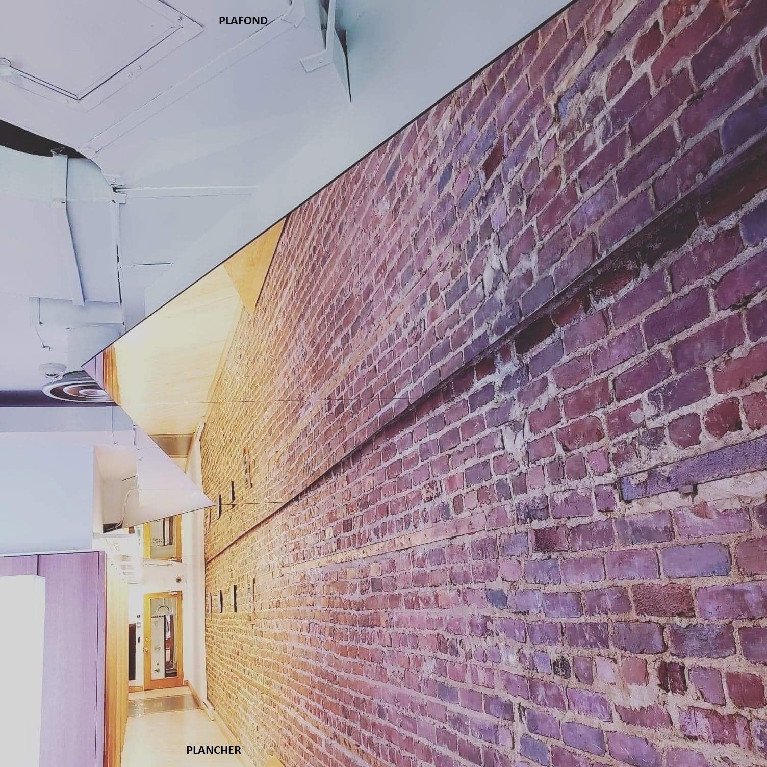 Un long couloir avec un mur de briques et un plafond