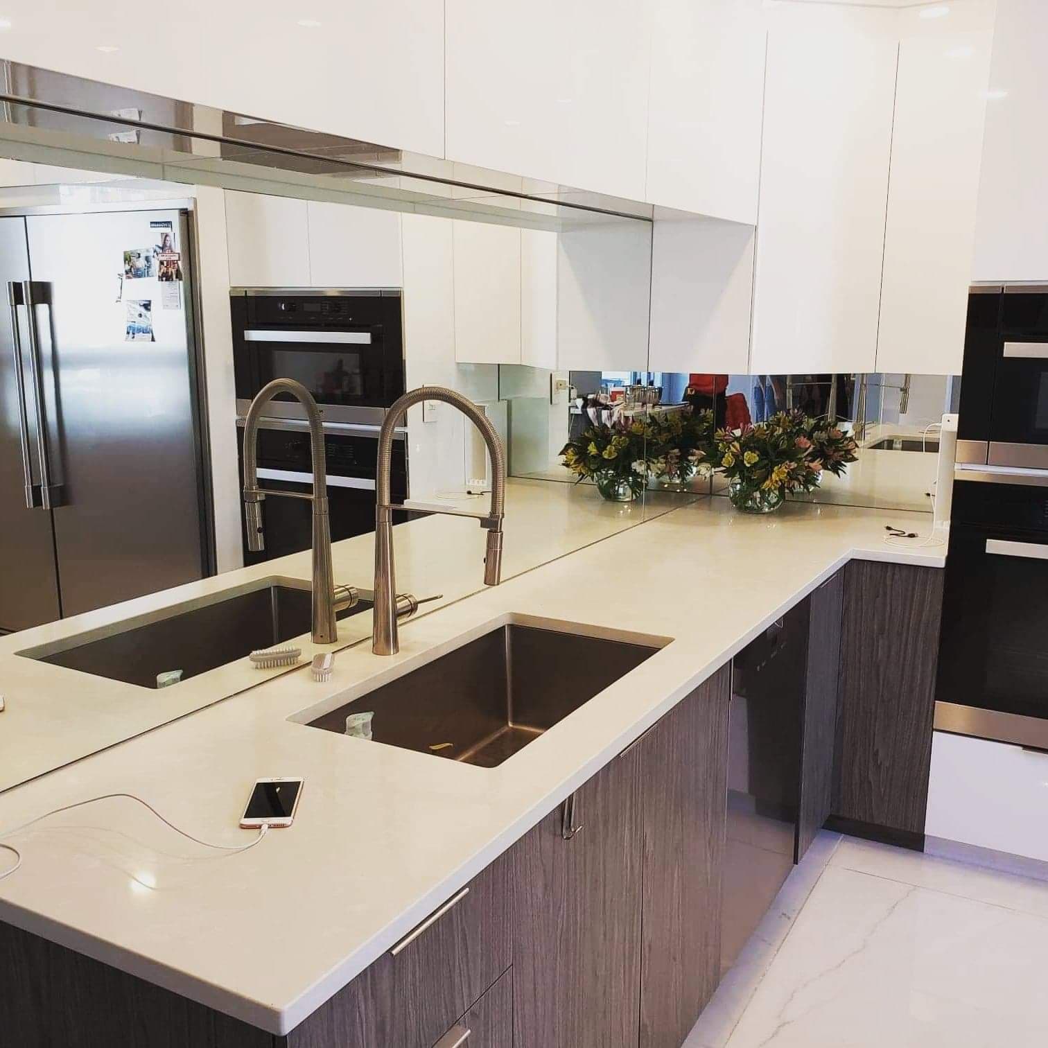 Une cuisine avec deux éviers et un grand miroir