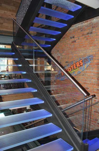 Un escalier avec des lumières bleues sur les marches et un mur de briques derrière.