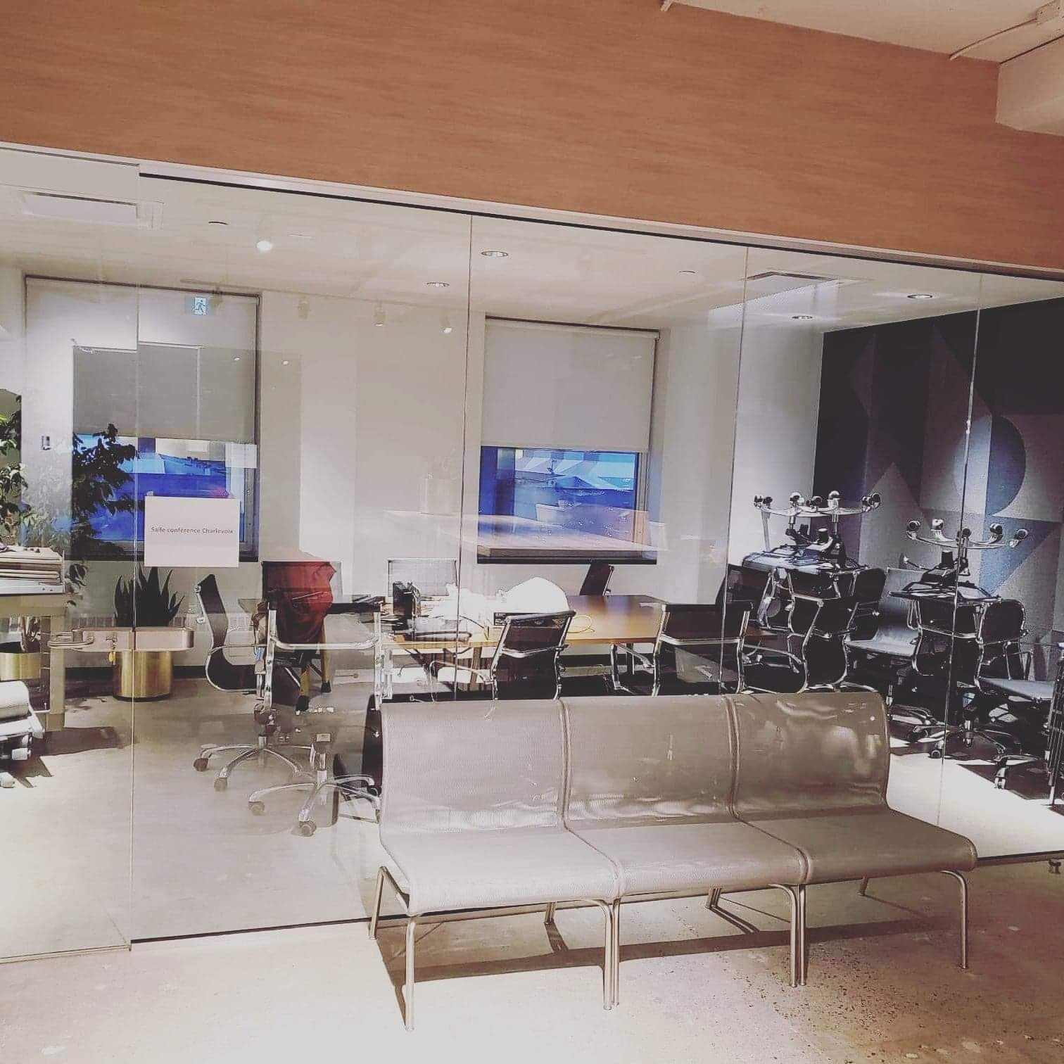 Une salle d'attente avec un canapé et des chaises devant un mur de verre