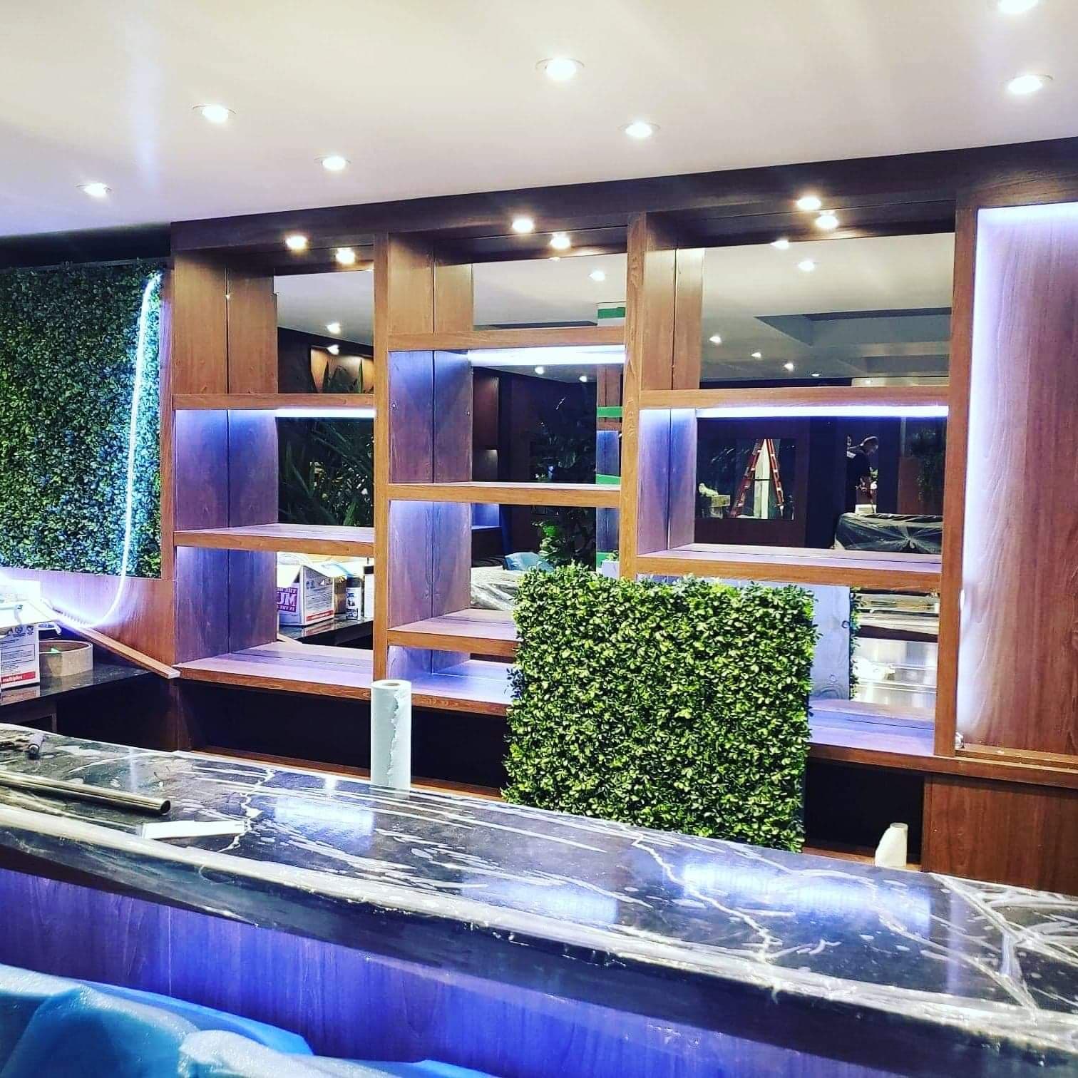 Un bar dans un restaurant avec un mur végétal derrière.