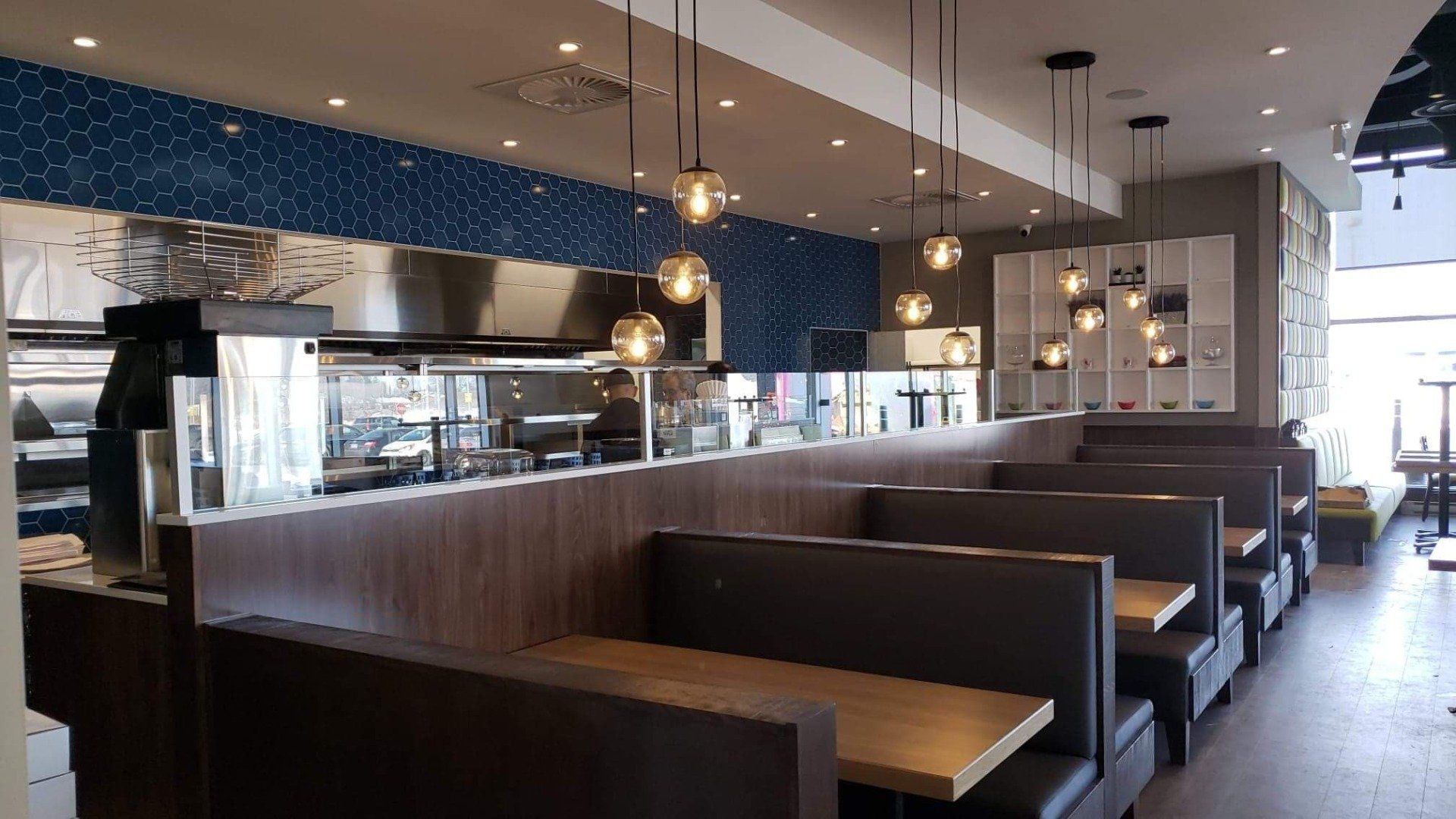 Un restaurant avec des tables et des cabines et une cuisine en arrière-plan.