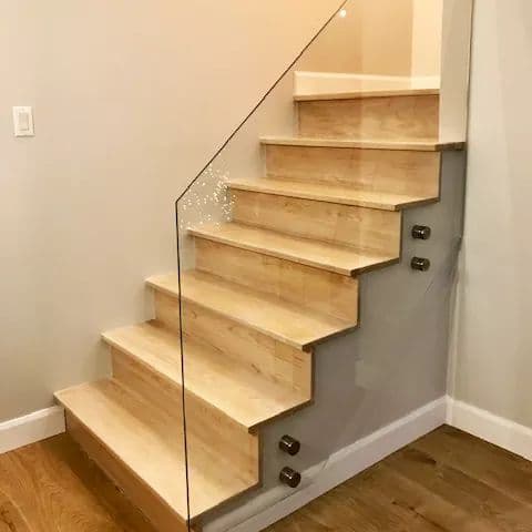 Un escalier en bois avec une rampe en verre dans une pièce.