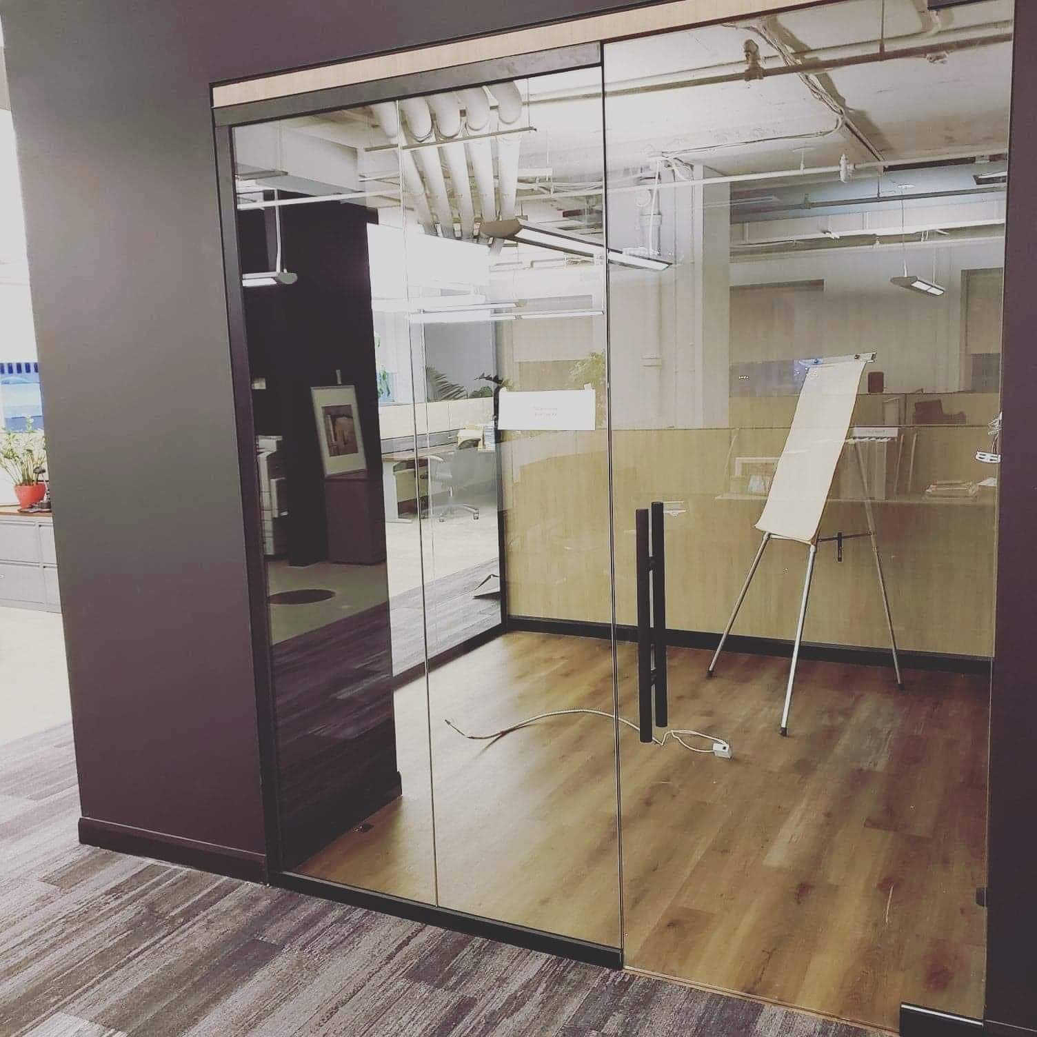 Une pièce avec une porte vitrée et un tableau blanc sur un support.