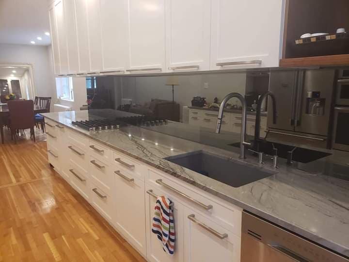 Une cuisine avec des armoires blanches, des appareils électroménagers en acier inoxydable, un évier et une cuisinière.