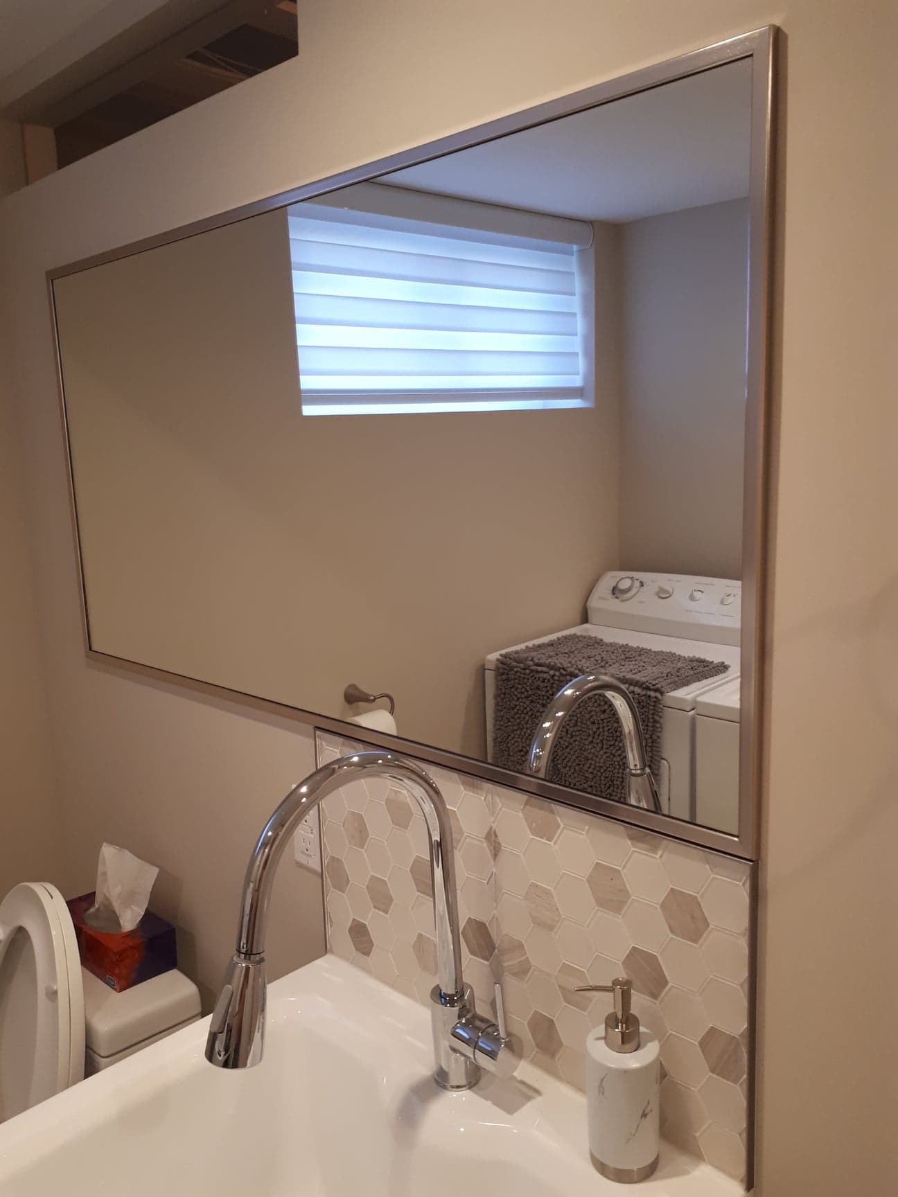 Une salle de bain avec lavabo, miroir et laveuse et sécheuse.