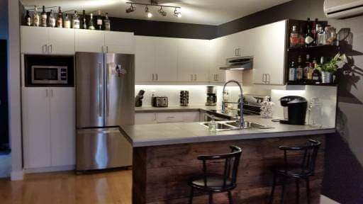 Une cuisine avec un réfrigérateur en acier inoxydable, un évier et un bar.