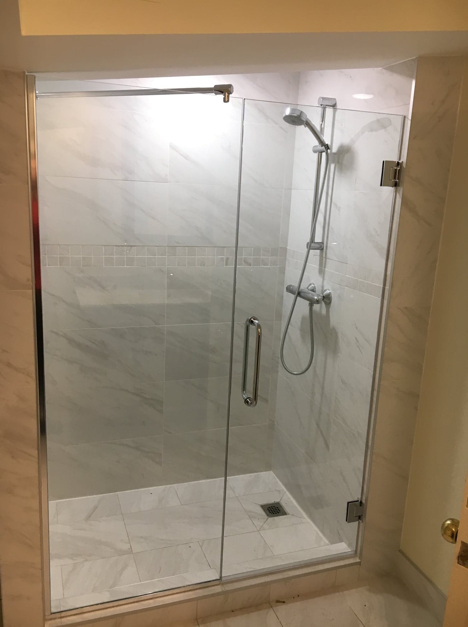 Une salle de bain avec une porte de douche en verre et une pomme de douche.