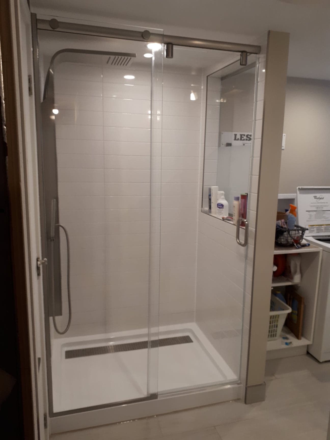 Une salle de bain avec une porte de douche coulissante en verre et une pomme de douche.