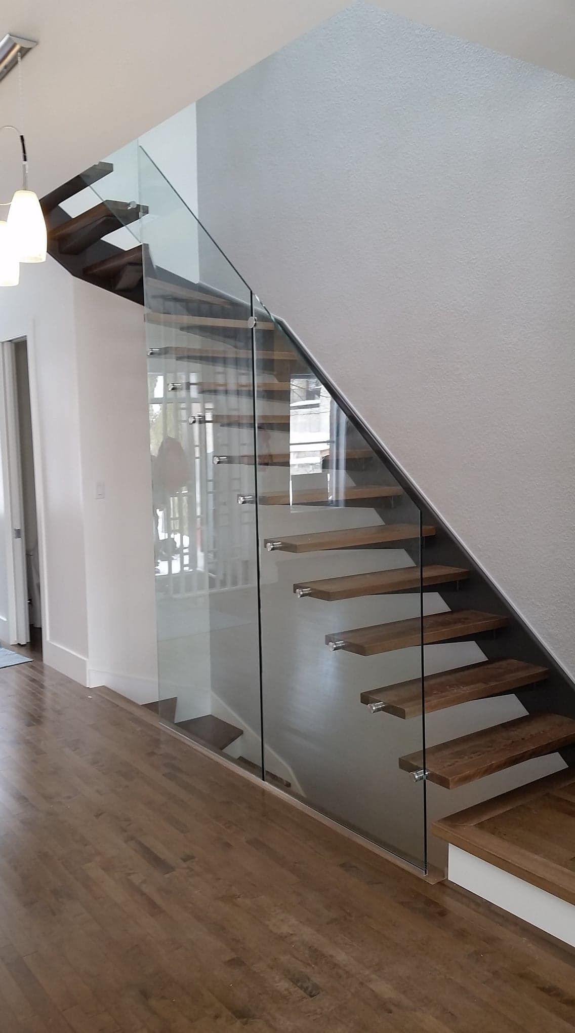 Un escalier avec des marches en bois et une rampe en verre dans une maison.