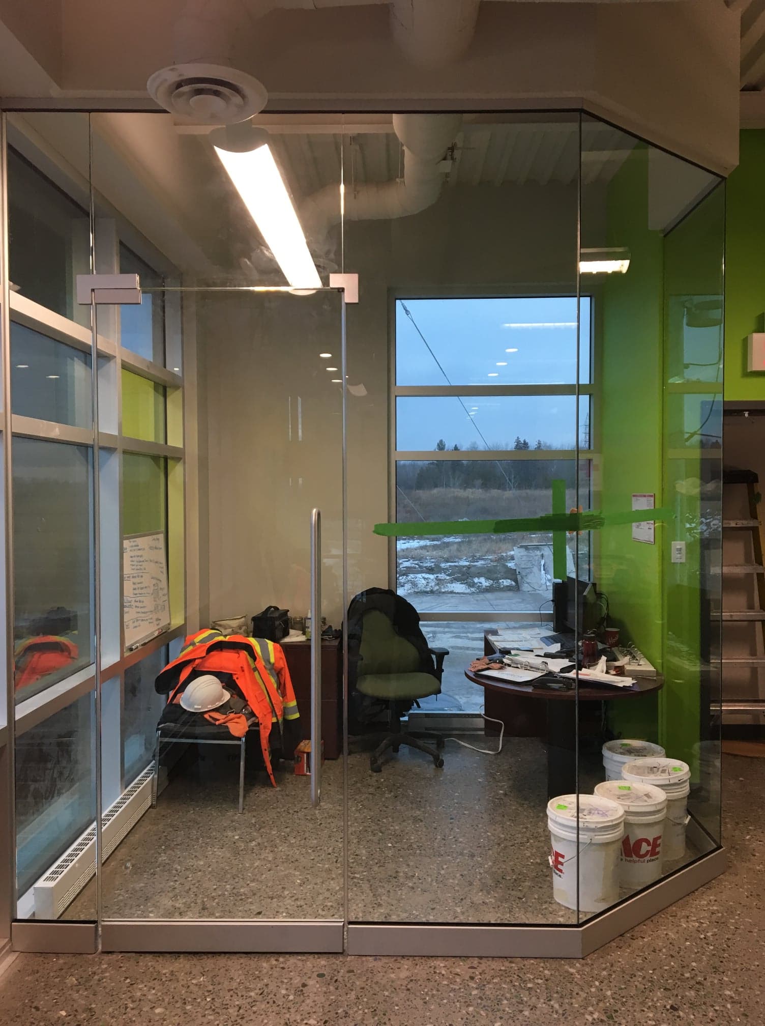 Une pièce avec un mur en verre, un bureau et une chaise.