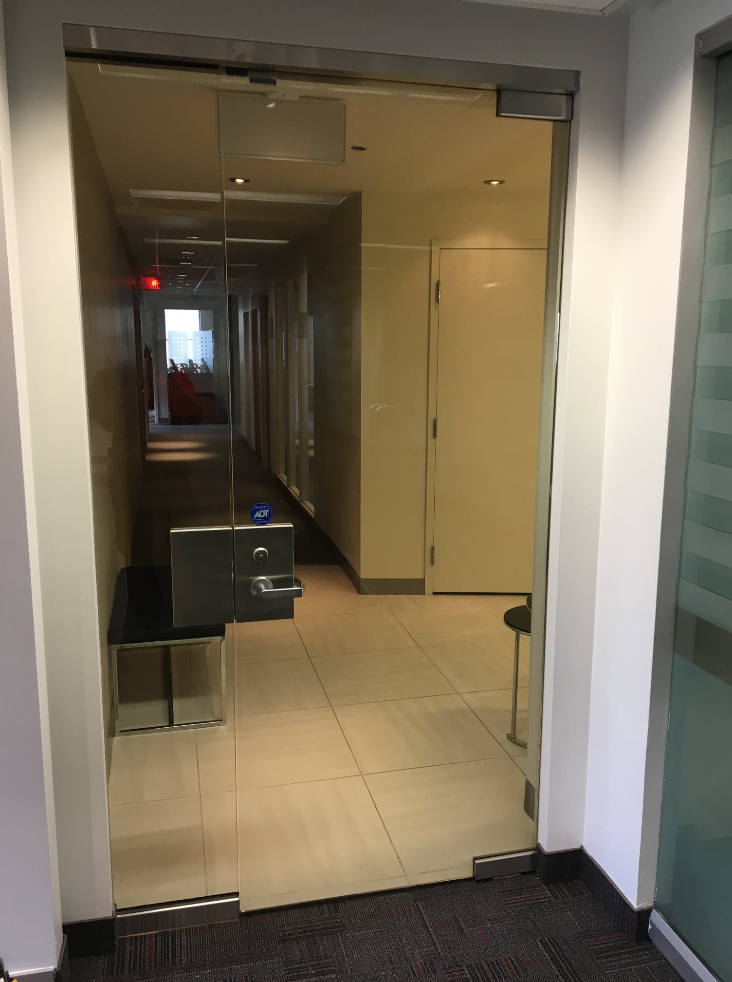 Un couloir avec une porte vitrée menant à une pièce.