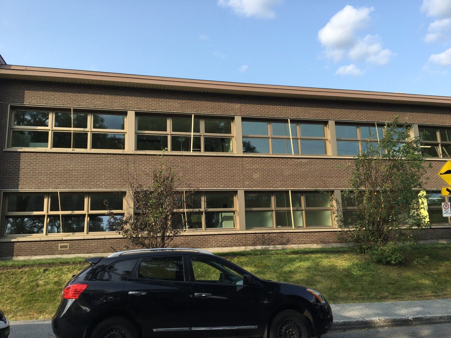 A black car is parked in front of a large brick building