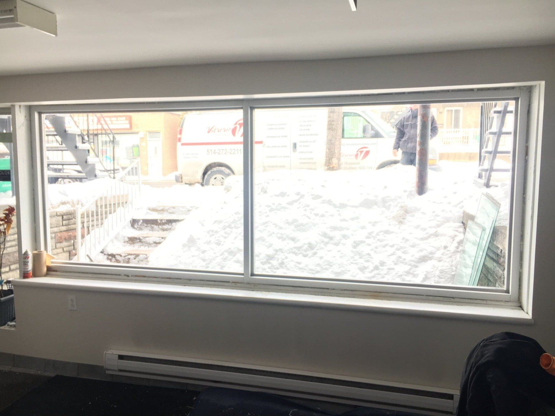 A large window in a room with a view of a snowy street.