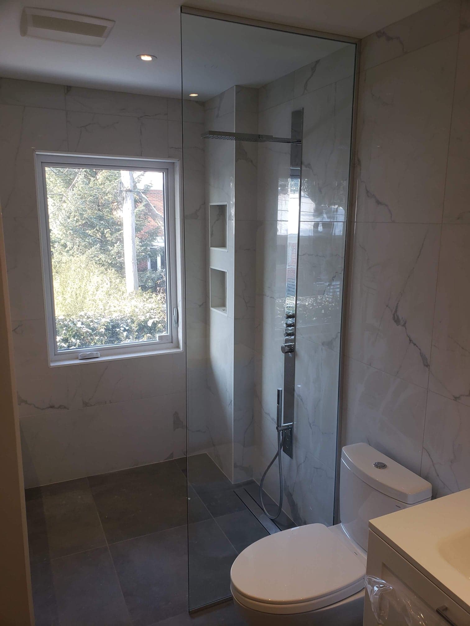 Une salle de bain avec WC, lavabo, douche et fenêtre.