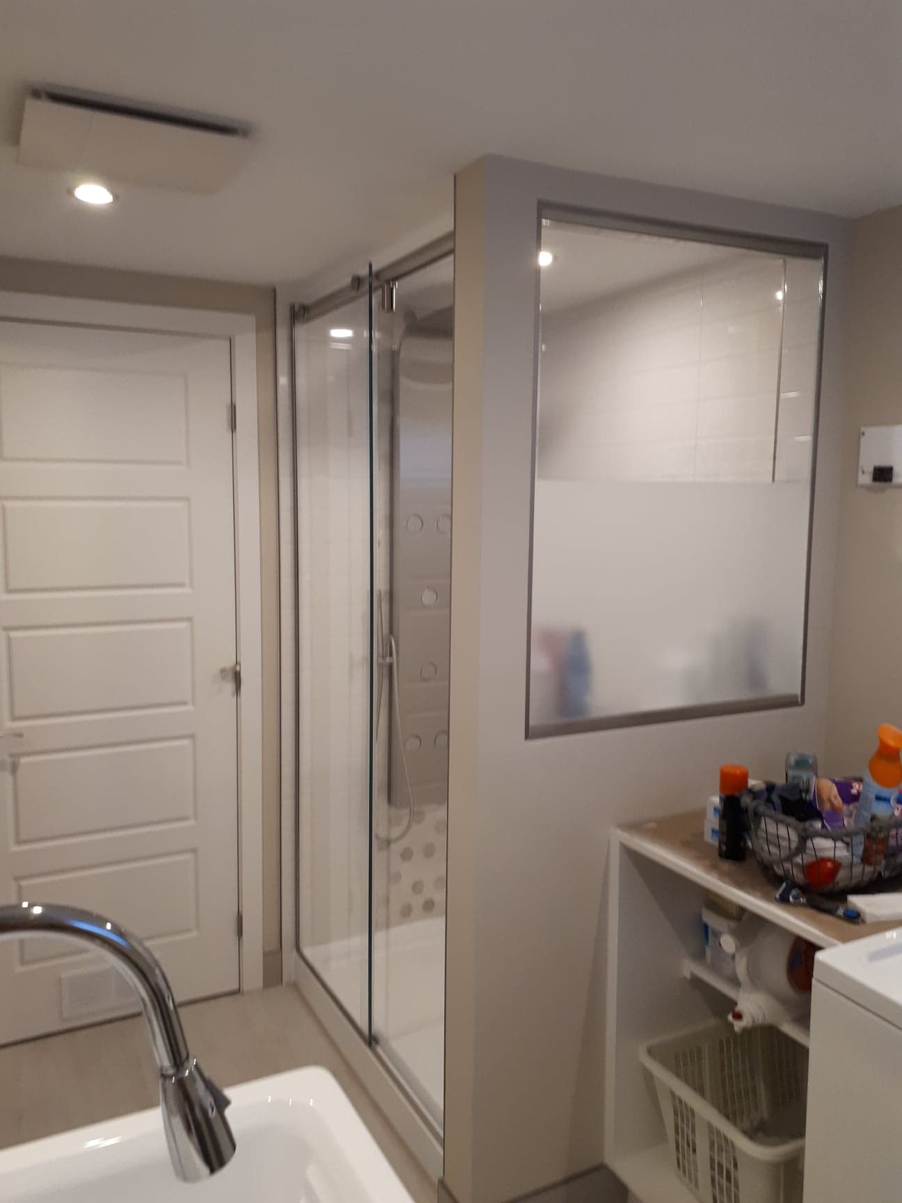 Une salle de bain avec lavabo, laveuse et sécheuse et une douche à l'italienne.