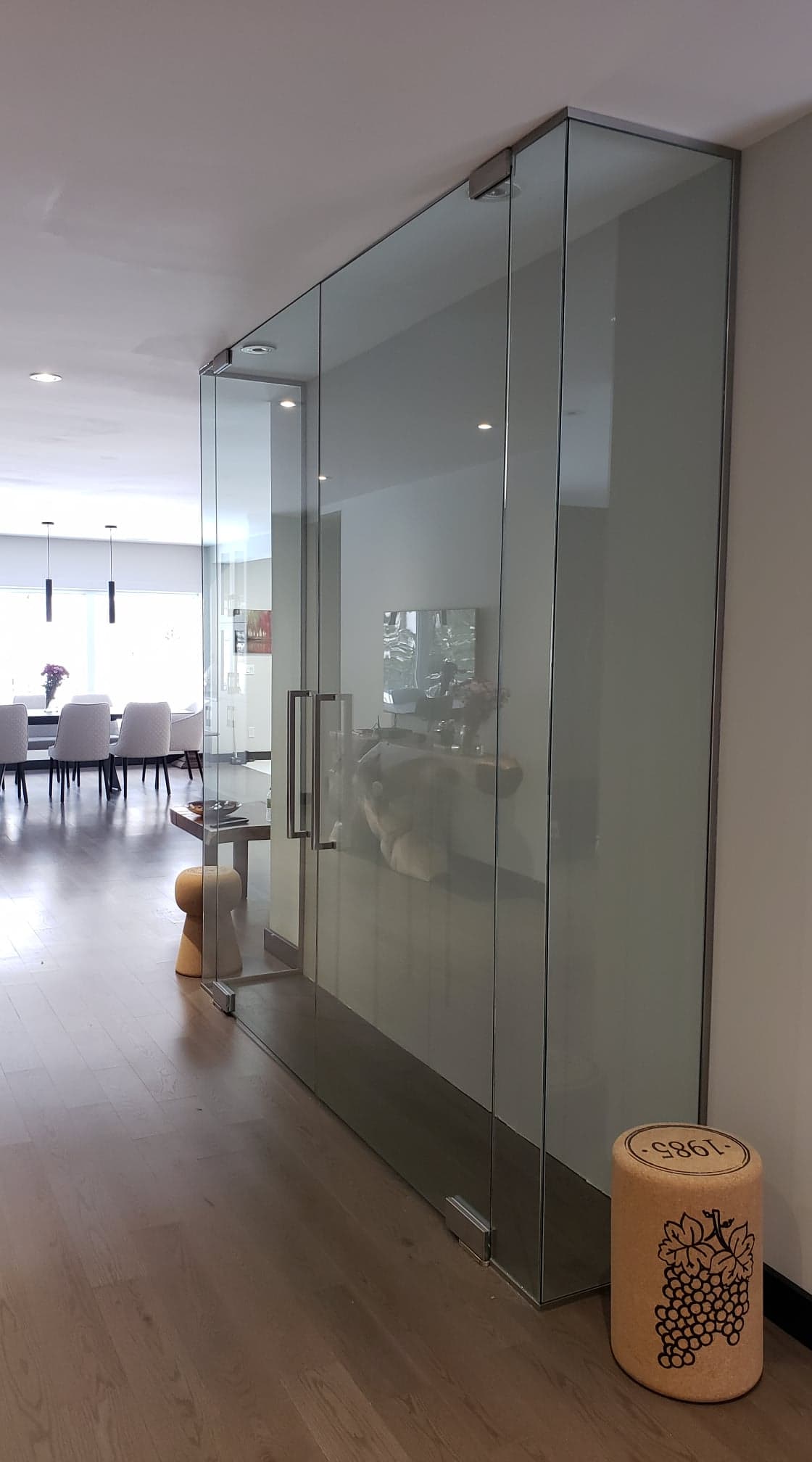 Un couloir avec un mur en verre et un tabouret au premier plan.