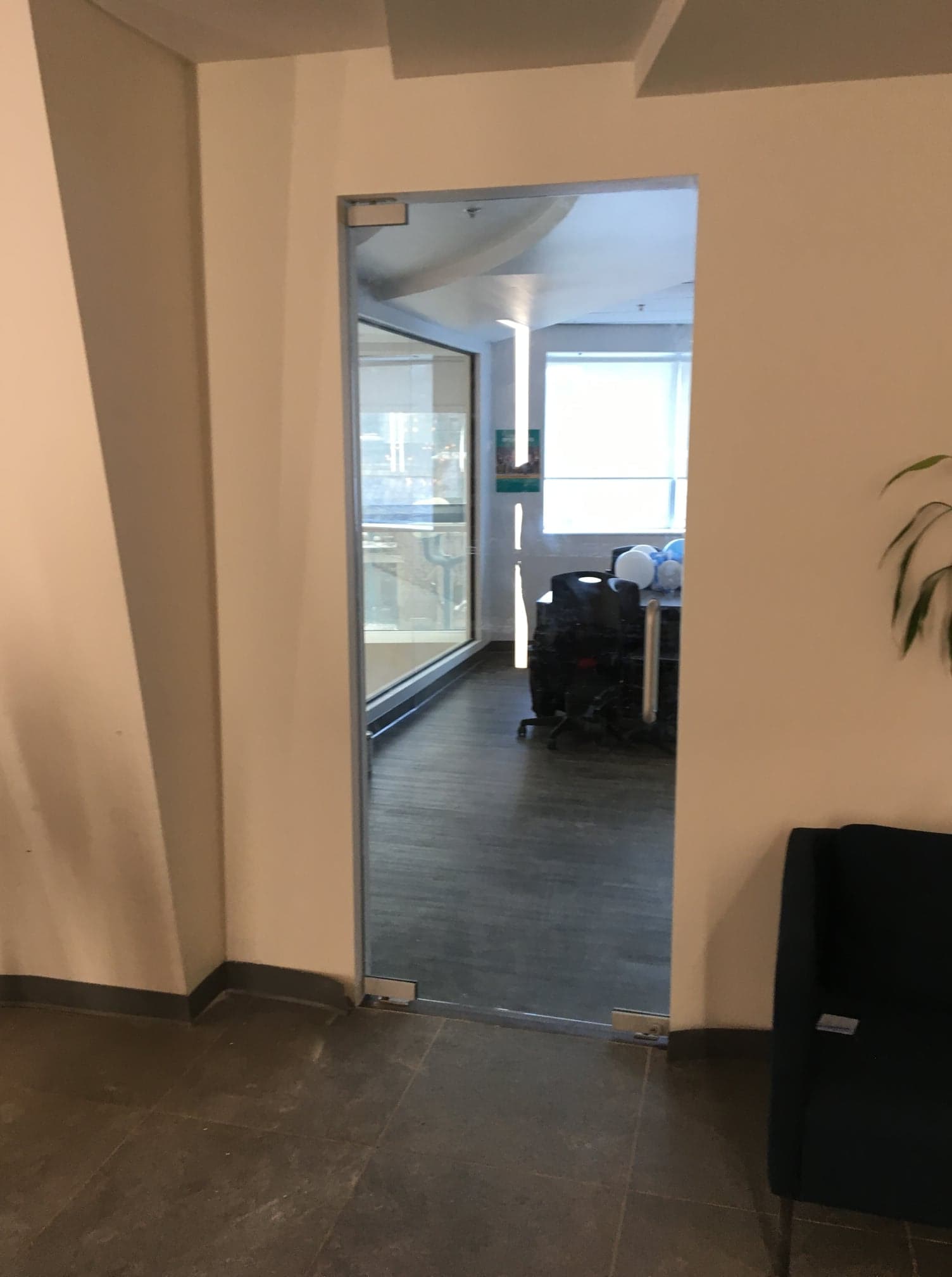 Une porte vitrée est ouverte sur une pièce avec un bureau et des chaises.