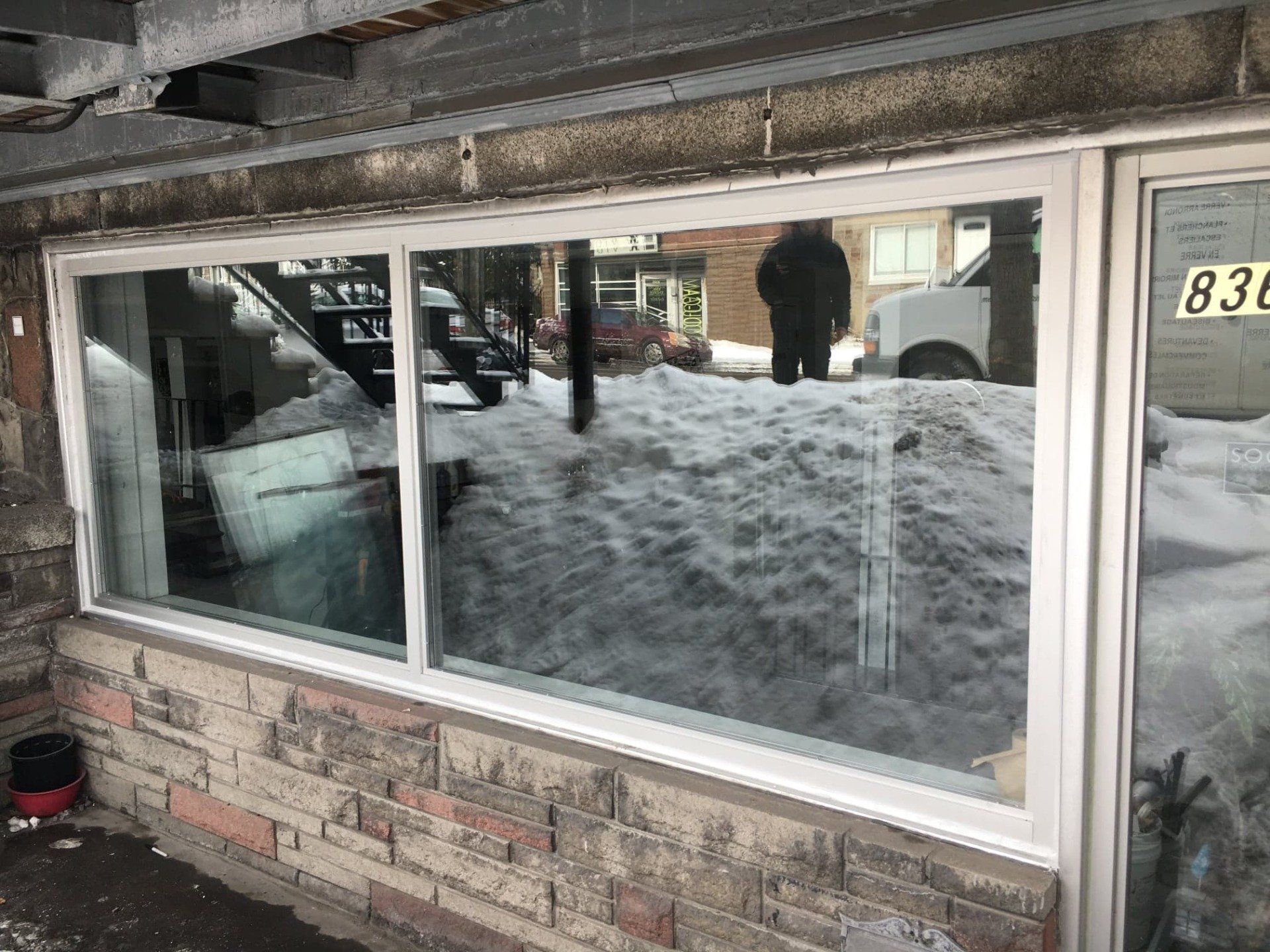 A large window with a reflection of a snowy street in it.