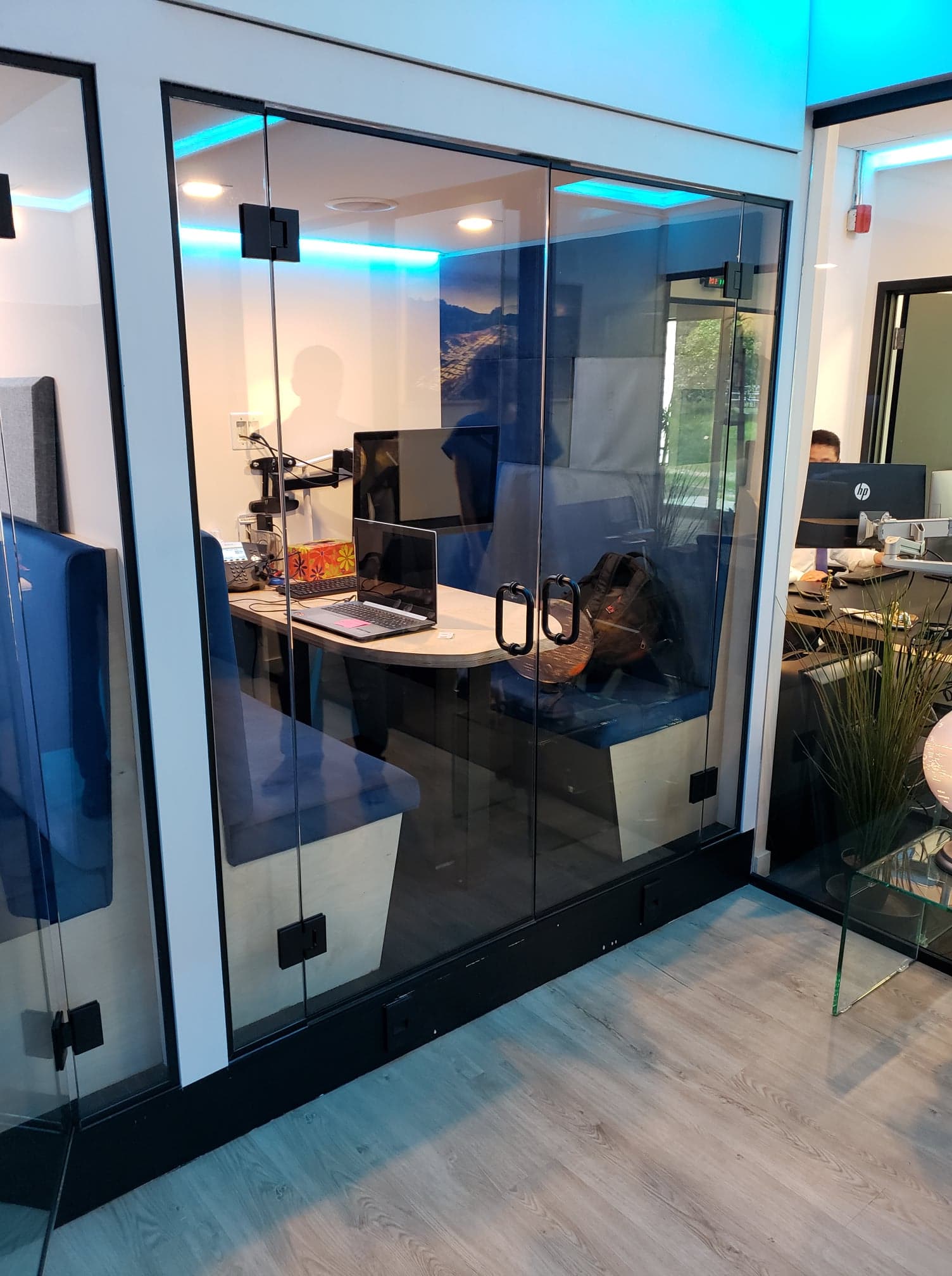 Une pièce avec un mur en verre et une table avec un ordinateur portable dessus.