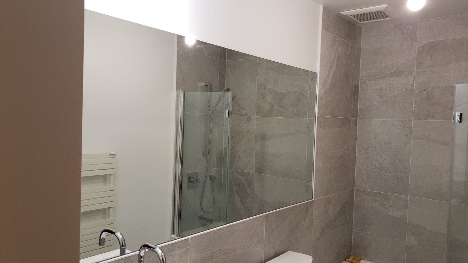 Une salle de bain avec un grand miroir et une cabine de douche.