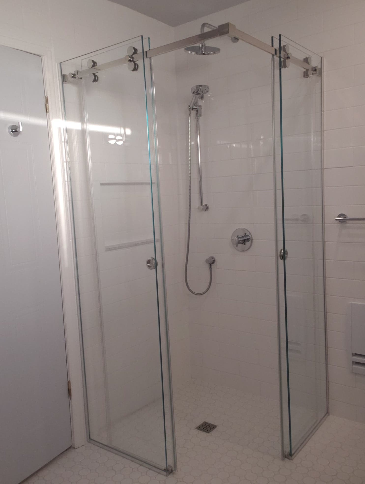 Une cabine de douche avec des portes coulissantes en verre et une pomme de douche dans une salle de bain.