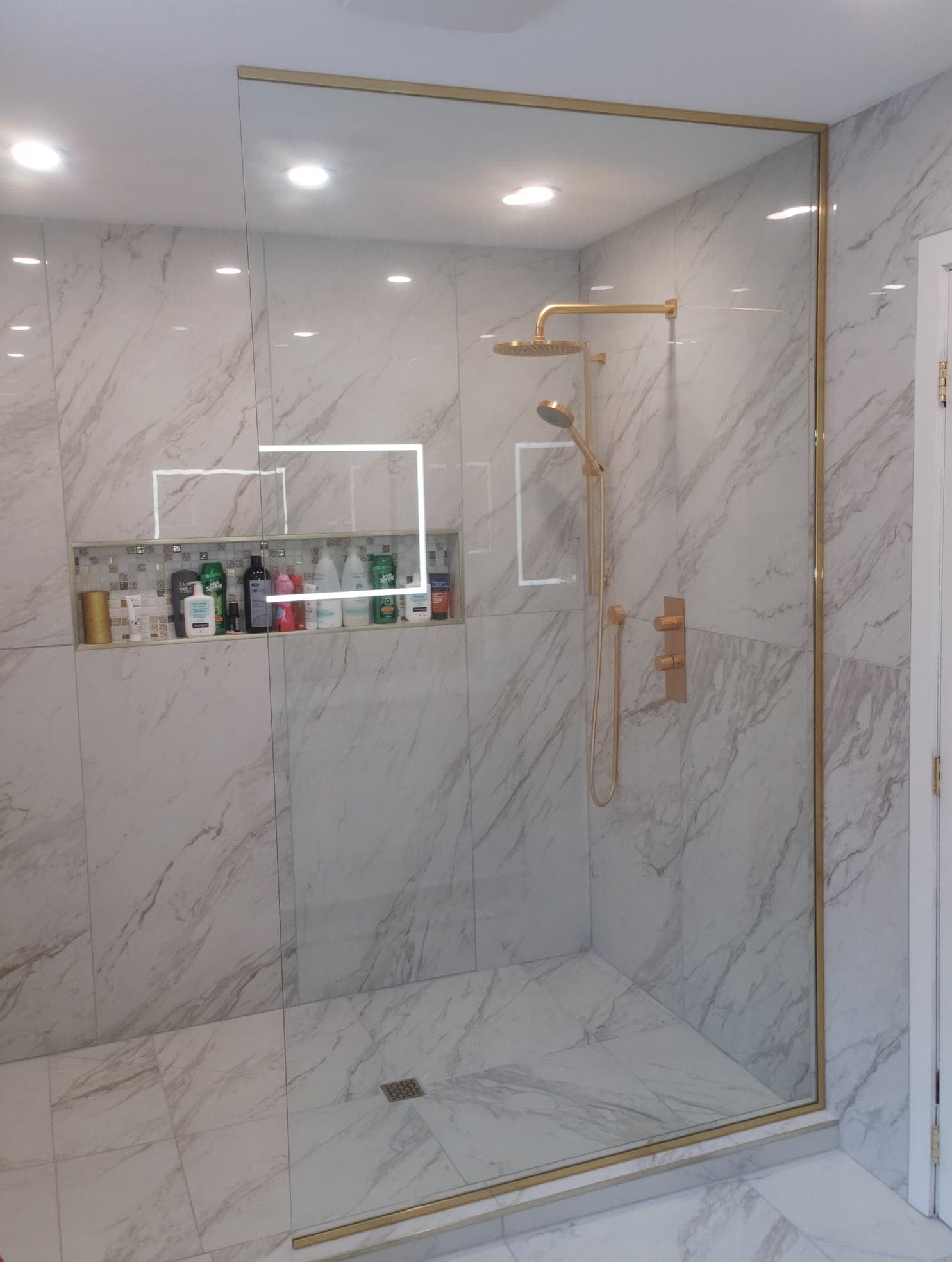 Une salle de bain avec douche à l'italienne et un mur en marbre.