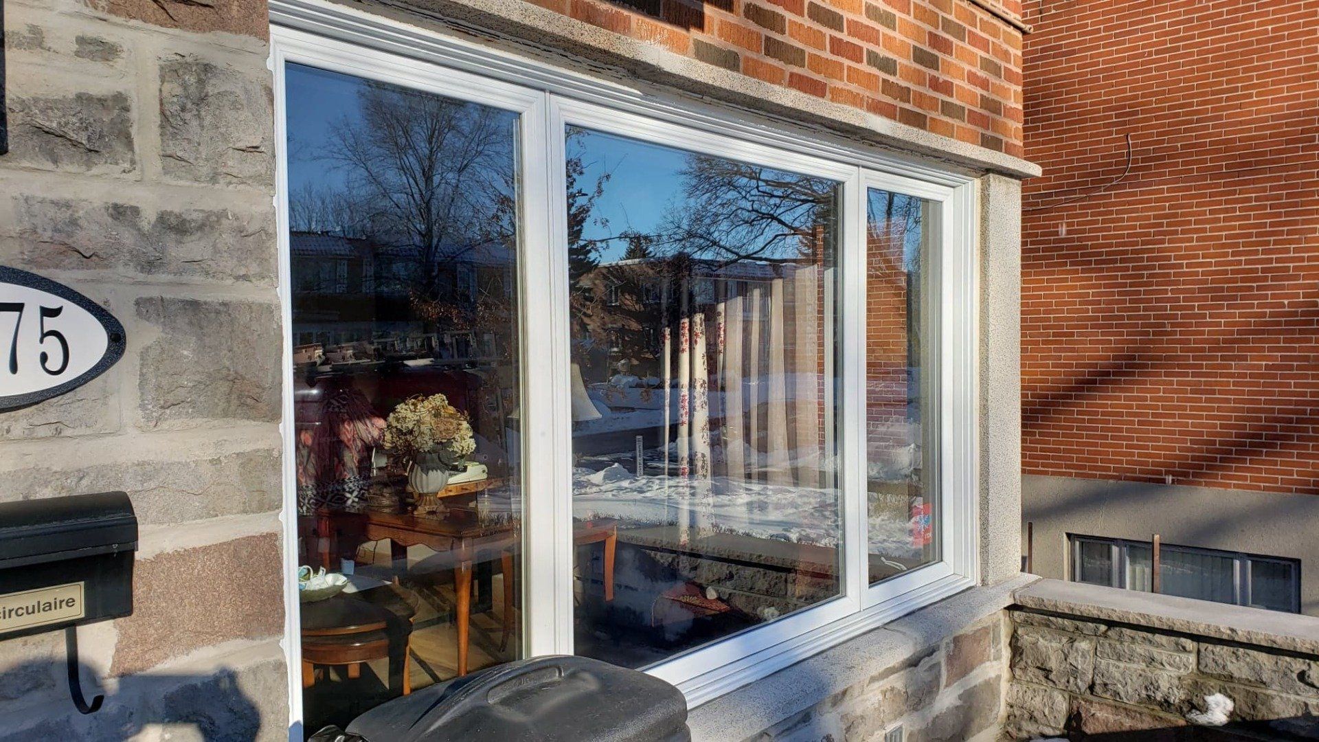 Un bâtiment en brique avec une grande fenêtre et une boîte aux lettres.