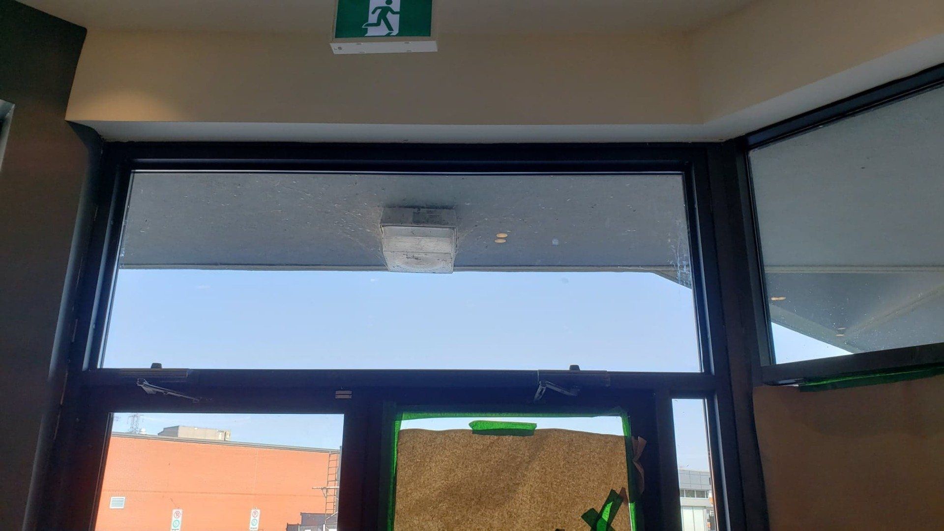 Un panneau de sortie vert est au-dessus d'une fenêtre dans un bâtiment.